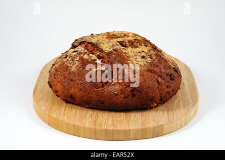 Hausgemachte frische ausgesät Brotlaib auf einem Holzbrett vor einem einfarbigen Hintergrund. Stockfoto