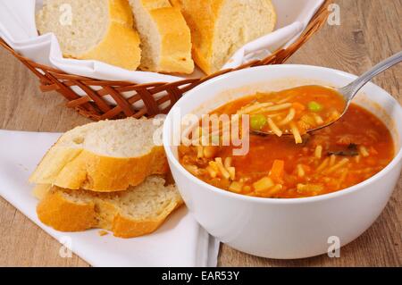 Hausgemachte vegetarische Minestrone-Suppe mit Brot serviert. Stockfoto