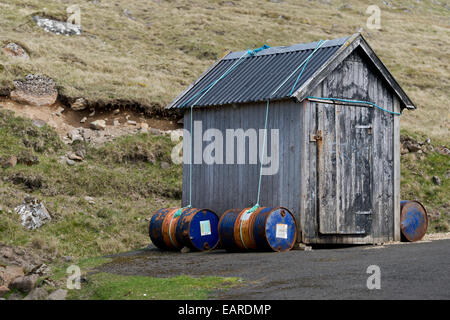Fässer gefüllt mit Sand, die Hütte auf dem Boden zu halten bei starkem Wind, Kirkja, Fugloy, Norðoyar, Färöer Inseln, Dänemark Stockfoto