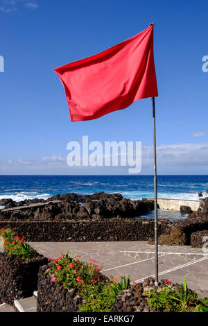 Rote Fahne fliegen, um der Gefahr bei rauer See in Garachico, Teneriffa, Kanarische Inseln, Spanien zu warnen. Stockfoto