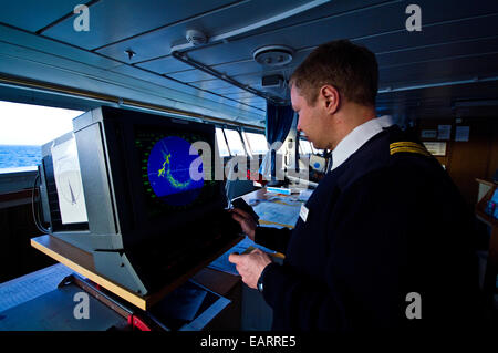 Ein Offizier vom Dienst an Bord eines Schiffes Brücke untersucht einem Radarschirm. Stockfoto