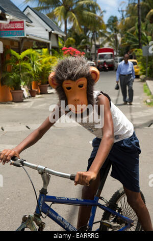 Mauritius, Grand Baie, Kind trägt Affenmaske, während Radfahren Stockfoto