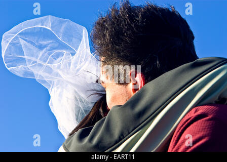 Ein Bräutigam küsst die Braut während ihrer windigen Hochzeit in der Antarktis. Stockfoto