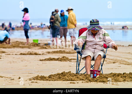 Eine ältere Frau schläft in einem Strandkorb umgeben von Pipi Fischer. Stockfoto