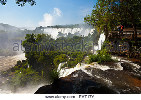 Touristen stehen auf einer Aussichtsplattform mit Blick auf die Iguazu Wasserfälle. Stockfoto