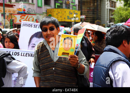 La Paz, Bolivien. November 2014. Ein Demonstrant hält ein Bild von einem der 43 vermissten Studenten in Mexiko während eines marsches, um Gerechtigkeit und Protest gegen die Behandlung des Falls durch die mexikanische Regierung und Korruption zu fordern. Heute ist ein globaler Aktionstag für Ayotzinapa vorgesehen; in Mexiko ist ein nationaler Streik geplant, und weltweit finden zahlreiche Proteste statt, um Unterstützung zu zeigen. Die Schüler, die von einer Lehrerschule stammten, verschwanden nach Zusammenstößen mit der Polizei in der Nacht des 26. September in der Stadt Iguala. Quelle: James Brunker / Alamy Live News Stockfoto