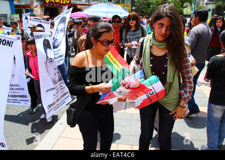 La Paz, Bolivien. November 2014. Eine Demonstrantin trägt mexikanische Fahnen mit 43 Ayotzinapa, die sie an andere Demonstranten während eines marsches aushändigen, um Gerechtigkeit für die 43 vermissten Studenten in Mexiko zu fordern und gegen die Behandlung des Falls durch die mexikanische Regierung zu protestieren. Heute ist ein globaler Aktionstag für Ayotzinapa vorgesehen; in Mexiko ist ein nationaler Streik geplant, und weltweit finden zahlreiche Proteste statt, um Unterstützung zu zeigen. Die Studenten verschwanden nach Zusammenstößen mit der Polizei in der Nacht des 26. September in der Stadt Iguala. Quelle: James Brunker / Alamy Live News Stockfoto