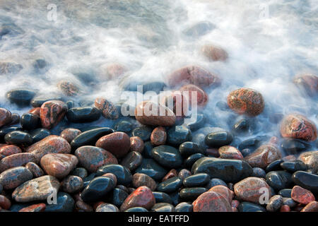 Nahaufnahme von bunten Pflaster bedeckt von Welle am Strand bei Flut Stockfoto