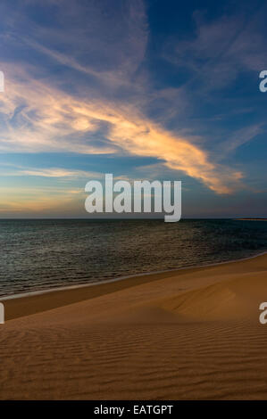 Ein Sonnenuntergang Nachleuchten wirft einen pastelligen Farbton auf einem einsamen Wüste Strand. Stockfoto