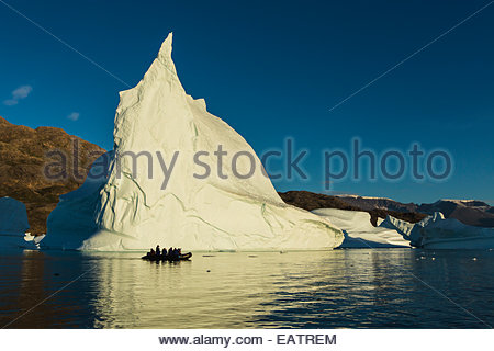 Ein Schlauchboot mit Öko-Touristen vor einem Eisberg. Stockfoto