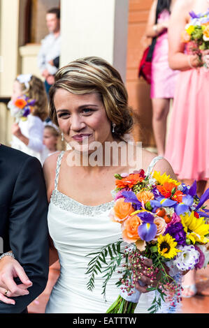 Eine glückliche, errötende Braut mit ihrem Strauß bei einer griechisch-orthodoxen Hochzeit. Stockfoto