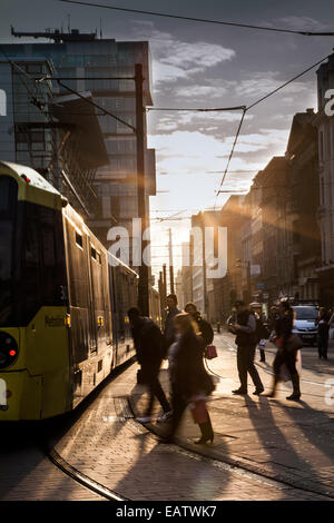 Manchester, Low Evening Winter Sun in Fountain Street, in der Nähe von Piccadilly Gardens, shoppen vor der Sonne und produzieren lange Schatten, die die Straße überqueren, während sie einen schönen sonnigen Abschluss des Tages in Manchester genießen. Straßenbahnlinien und -Route im Stadtzentrum von Manchester Metrolink. Stockfoto