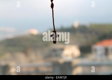 Eine hängende kleine verknotete Rosenkranz mit Kruzifix auf einen natürlichen Hintergrund. Stockfoto