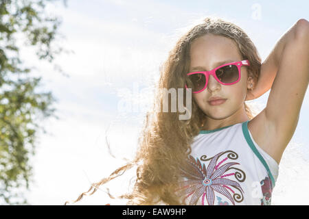 Junge Mädchen in Sonnenbrille Festsetzung ihre langen blonden Haare in der Sonne an einem heißen Nachmittag. Stockfoto