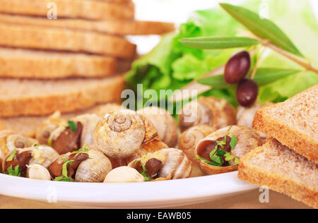 Lecker zubereitet Schnecken mit Brot und Oliven auf dem Teller, Luxus-Dinner in teuren Restaurant, französische Feinkost Stockfoto