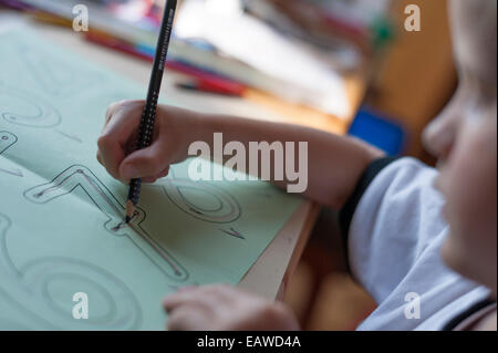 eine 7-jährige Schulkind tut Schreibübungen als Hausaufgabe für die Grundschule. Stockfoto