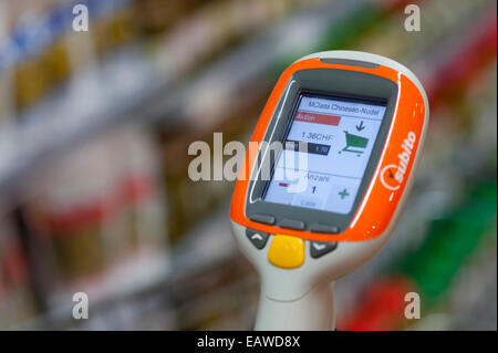 Ein handheld Subito Selfscanning-Gerät fest mit einem Warenkorb in einem Migros-Supermarkt in Zürich, Schweiz. Stockfoto