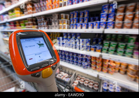 Ein handheld Subito Selfscanning-Gerät fest mit einem Warenkorb in einem Migros-Supermarkt in Zürich, Schweiz. Stockfoto