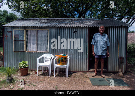 Ein Mann steht vor einer Wellpappe Zinn Gartenhaus, die sein Zuhause ist. Stockfoto