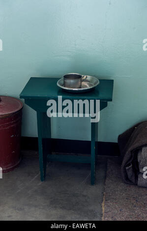 Eine Tabelle enthält eine Tasse und Schale in der Zelle von Nelson Mandela bewohnt. Stockfoto