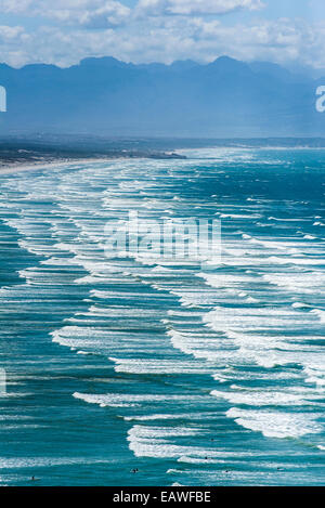 Endlose Wellen Rollen auf einen langen, weißen Sandstrand unter ein Sommerhimmel. Stockfoto