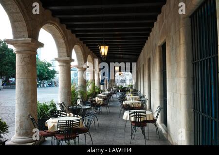 Tische erwarten Gäste innerhalb einer Arkade entlang der Plaza de Armas, Havanna. Stockfoto