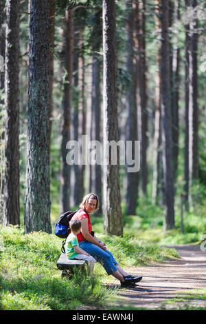 Mutter und Sohn sitzen auf einer Bank im Wald Stockfoto