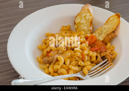 Italienische Tomaten Pasta serviert mit Knoblauchbrot Stockfoto