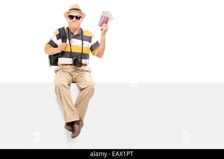 Ältere Touristen mit Pass mit Geld sitzt auf einem Panel isoliert auf weißem Hintergrund Stockfoto