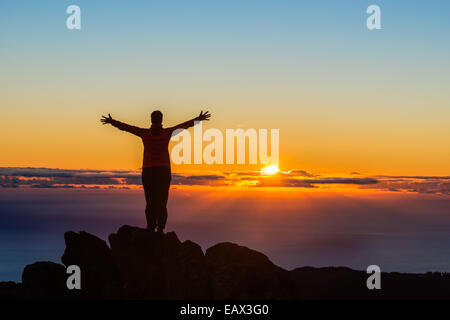 Wanderer mit Armen angehoben auf einem Berg bei Sonnenaufgang Stockfoto