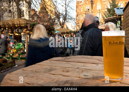 Ein erfrischendes Bier in ein graviertes Glas mit Logo "Manchester Markets" und Shopper im Hintergrund Manchester, UK Stockfoto