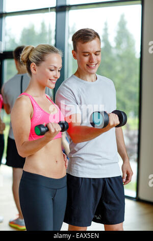 lächelnde junge Frau mit personal Trainer im Fitness-Studio Stockfoto