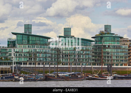 Boote und Lastkähne festgemacht an der Themse in der Nähe von Luxus Glas fronted riverside Apartments Osten London England Europa. Stockfoto