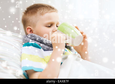 krank junge mit Grippe im Bett trinken aus der Tasse zu Hause Stockfoto