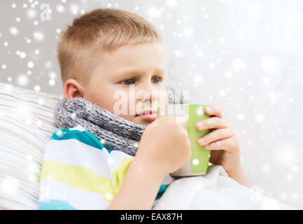 krank junge mit Grippe im Bett trinken aus der Tasse zu Hause Stockfoto