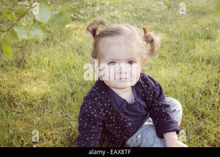 Babymädchen sitzen auf dem Rasen, Porträt Stockfoto