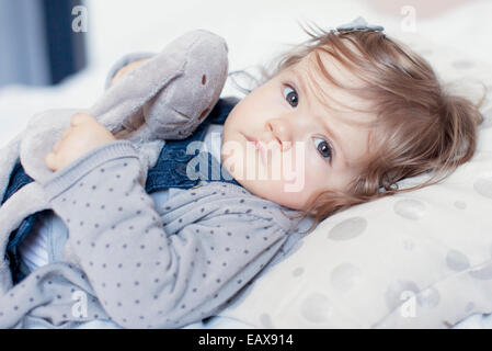 Babymädchen liegend mit Stofftier, Porträt Stockfoto