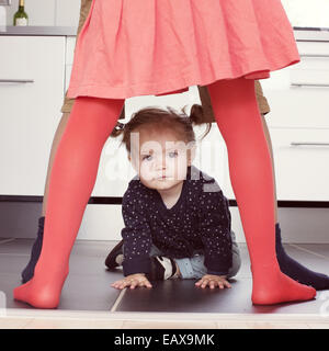 Babymädchen durch Geschwister Beine kriechen Stockfoto