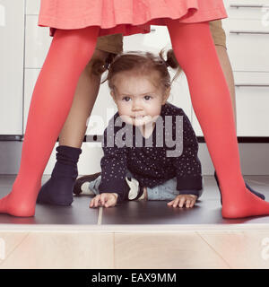 Babymädchen durch Geschwister Beine kriechen Stockfoto