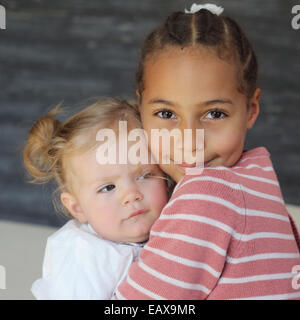 Mädchen umarmt Babymädchen, Porträt Stockfoto