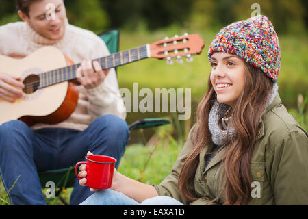 lächelnde paar mit Gitarre auf dem Campingplatz Stockfoto