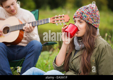 lächelnde paar mit Gitarre auf dem Campingplatz Stockfoto