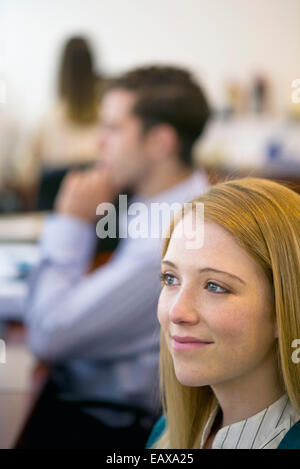 Junge Frau lächelt verträumt im Büro Stockfoto