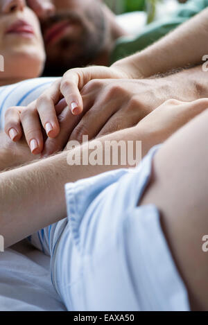 Paar liegend zusammen, halten die Hände Stockfoto