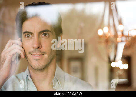 Mann mit Handy suchen Fenster Stockfoto