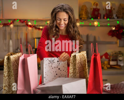 Lächelnde junge Frau mit Einkaufstüten in Weihnachten eingerichtet Küche Stockfoto