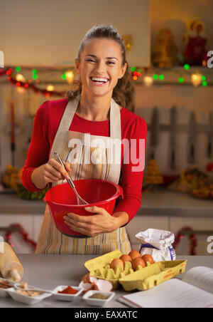 Porträt von lächelnden jungen Hausfrau reizwahrnehmenden Teig in Weihnachten eingerichtet Küche Stockfoto