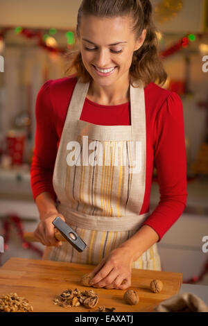 Glückliche junge Hausfrau hacken Walnüsse in Weihnachten eingerichtet Küche Stockfoto