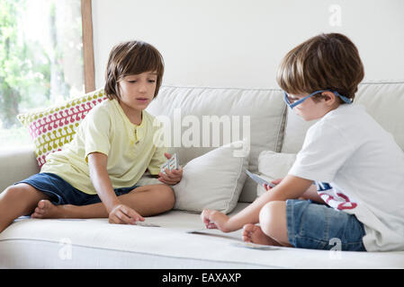 Jungen sitzen auf Sofa Spielkarten Stockfoto