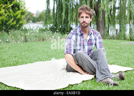 Mann sitzt auf einer Decke im freien Stockfoto